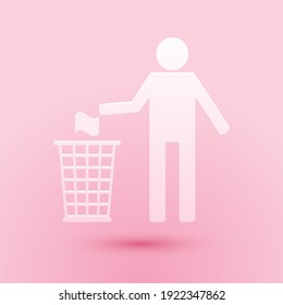 Paper cut Man throwing trash into dust bin icon isolated on pink background. Recycle symbol. Paper art style. Vector.