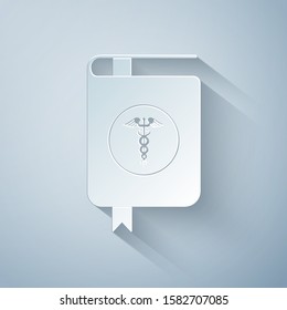 Paper cut Medical book and Caduceus medical symbol icon isolated on grey background. Medical reference book, textbook, encyclopedia. Scientific literature. Paper art style. Vector Illustration