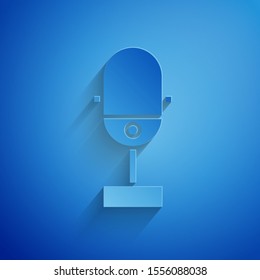 Paper cut Microphone icon isolated on blue background. On air radio mic microphone. Speaker sign. Paper art style. Vector Illustration