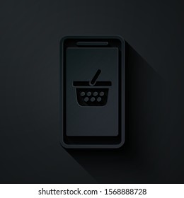 Paper cut Mobile phone and shopping basket icon isolated on black background. Online buying symbol. Supermarket basket symbol. Paper art style. Vector Illustration