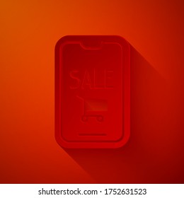Paper cut Mobile phone and shopping cart icon isolated on red background. Online buying symbol. Supermarket basket symbol. Paper art style. Vector Illustration