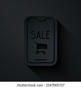 Paper cut Mobile phone and shopping cart icon isolated on black background. Online buying symbol. Supermarket basket symbol. Paper art style. Vector Illustration