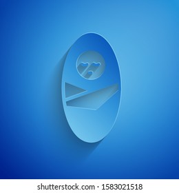 Paper cut Newborn baby infant swaddled or swaddling icon isolated on blue background. Baby kid child wrapped in blanket clothes. Paper art style. Vector Illustration