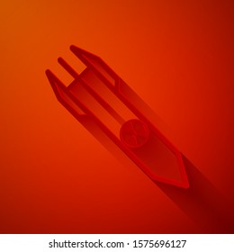 Paper cut Nuclear rocket icon isolated on red background. Rocket bomb flies down. Paper art style. Vector Illustration