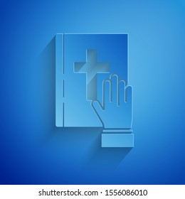 Paper cut Oath on the Holy Bible icon isolated on blue background. The procedure in court. Truth and truth. Promise before god. Paper art style. Vector Illustration