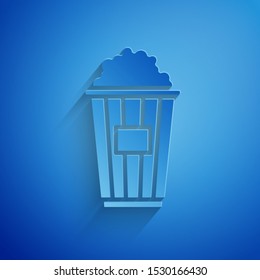 Paper cut Popcorn in cardboard box icon isolated on blue background. Popcorn bucket box. Paper art style. Vector Illustration