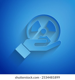 Paper cut Radioactive in hand icon isolated on blue background. Radioactive toxic symbol. Radiation Hazard sign. Paper art style. Vector