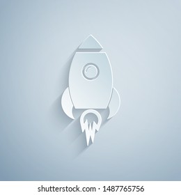 Paper cut Rocket ship with fire icon isolated on grey background. Space travel. Paper art style. Vector Illustration