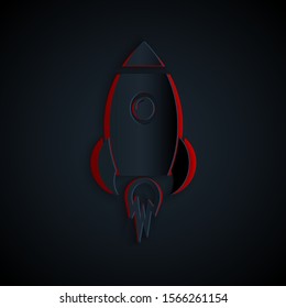 Paper cut Rocket ship with fire icon isolated on black background. Space travel. Paper art style. Vector Illustration
