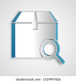 Paper cut Search package icon isolated on grey background. Parcel tracking symbol. Magnifying glass and cardboard box. Logistic and delivery. Paper art style. Vector Illustration