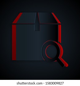 Paper cut Search package icon isolated on black background. Parcel tracking symbol. Magnifying glass and cardboard box. Logistic and delivery. Paper art style. Vector Illustration