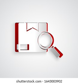 Paper cut Search package icon isolated on grey background. Parcel tracking. Magnifying glass and cardboard box. Logistic and delivery. Paper art style. Vector Illustration