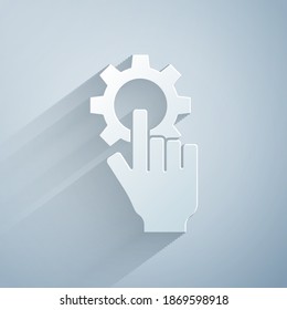Paper cut Settings in the hand icon isolated on grey background. Paper art style. Vector