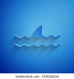 Paper cut Shark fin in ocean wave icon isolated on blue background. Paper art style. Vector Illustration