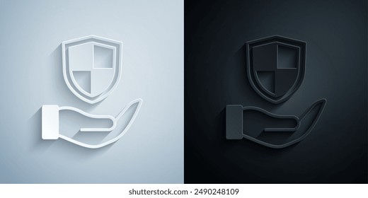 Escudo en el icono de la mano aislado en el fondo gris y negro. Concepto de seguro. Señal de guardia. Seguridad, seguridad, protección, concepto de privacidad. Estilo de arte de papel. Vector