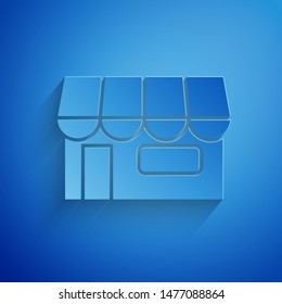 Paper cut Shopping building or market store icon isolated on blue background. Shop construction. Paper art style. Vector Illustration