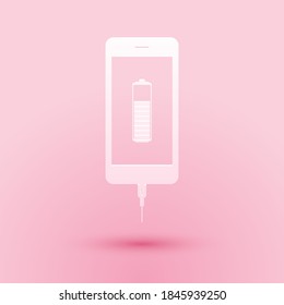 Paper cut Smartphone battery charge icon isolated on pink background. Phone with a low battery charge and with USB connection. Paper art style. Vector.