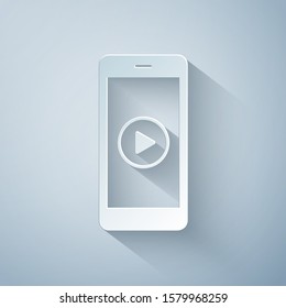 Paper cut Smartphone with play button on the screen icon isolated on grey background. Paper art style. Vector Illustration