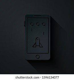 Paper cut Smartphone and playing in game icon isolated on black background. Mobile gaming concept. Paper art style. Vector Illustration