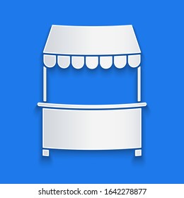 Paper cut Street stall with awning and wooden rack icon isolated on blue background. Kiosk with wooden rack. Paper art style. Vector Illustration