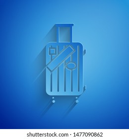 Paper cut Suitcase for travel and stickers icon isolated on blue background. Traveling baggage sign. Travel luggage icon. Paper art style. Vector Illustration