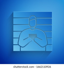 Paper cut Suspect criminal icon isolated on blue background. The criminal in prison, suspected near the board. Paper art style. Vector Illustration