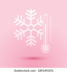 Papier schneiden Thermometer mit Schneeflocken Symbol einzeln auf rosafarbenem Hintergrund. Kunststil aus Papier. Vektorgrafik.
