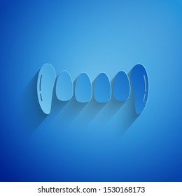 Paper cut Vampire teeth icon isolated on blue background. Happy Halloween party. Paper art style. Vector Illustration
