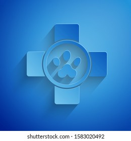 Paper cut Veterinary clinic symbol icon isolated on blue background. Cross hospital sign. Stylized paw print dog or cat. Pet First Aid sign. Paper art style. Vector Illustration