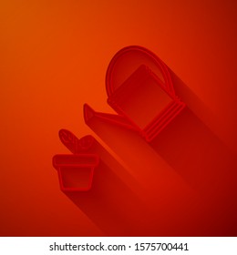 Paper cut Watering can sprays water drops above plant in pot icon isolated on red background. Irrigation symbol. Paper art style. Vector Illustration