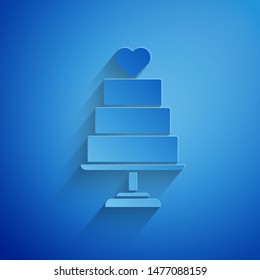 Paper cut Wedding cake with heart icon isolated on blue background. Paper art style. Vector Illustration
