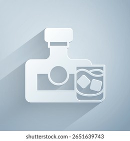 Paper cut Whiskey bottle and glass icon isolated on grey background. Paper art style. Vector