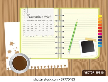 Paper and green Notebook With a cup of coffee and photo frame. on brown wood background. Calendar 2012 November Vector template for design work
