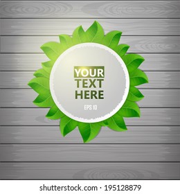 Paper label with green leaf on a wooden texture