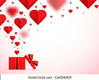 Paper origami of hearts, popping out of gift box on glossy pink background for love concept.