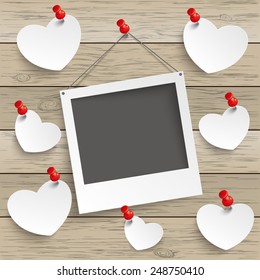 Paper photoframe and hearts with tacks on the wooden background. Eps 10 vector file.