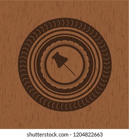 paper pin icon inside wooden emblem