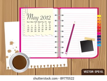 Paper and pink Notebook With a cup of coffee and photo frame. on brown wood background. Calendar 2012 May Vector template for design work