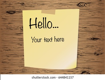 Paper sheet or post it on translucent sticky tape with shadow isolated on a wooden background. Text Hello on yellow note template for your design.