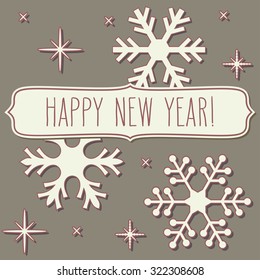 Paper snowflakes and a frame with New Year greetings over vintage brown background.
