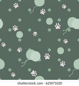 Pattern with cat paws and balls of yarn on green background. Vector illustration.