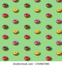 Pattern with colorful donuts isolated on a green background. Vector illustration.