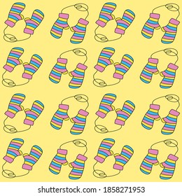 Pattern of cute knitted mittens on a yellow background. Warm striped mittens for protection from the cold. Autumn and winter clothing. Background for fabric, cover art, banners, and web design.