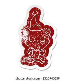peaceful quirky cartoon distressed sticker of a bear running wearing santa hat