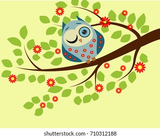 Peeping. a blue owl in red flowers with one closed and one open eye sitting on a branch of a flowering tree