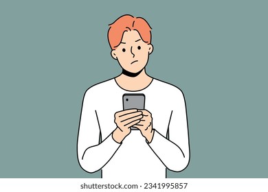 Pensive man with phone received warning text message with threat or bad news about storm warning. Confused young guy with disbelief reads spam sms in smartphone being skeptical about sender