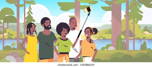 people group in forest using selfie stick taking photo on smartphone camera hiking concept african american friends standing together landscape background portrait horizontal