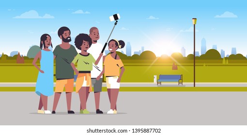 people group using selfie stick taking photo on smartphone camera african american friends standing together city urban park sunrise landscape background full length horizontal