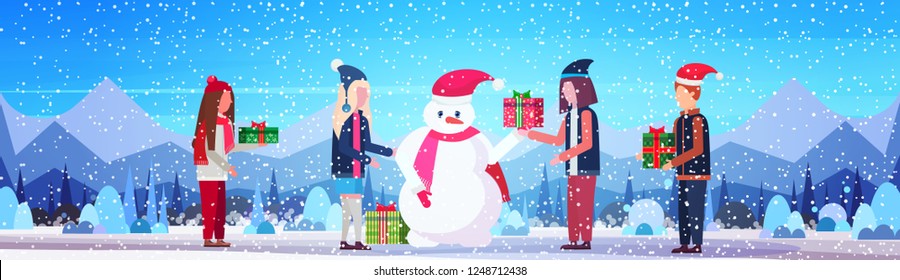 people hold wrapped gift box present for snowman merry christmas happy new year holiday concept winter mountains forest landscape background flat horizontal