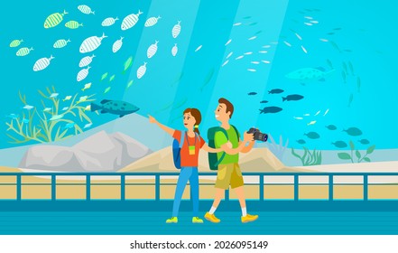 People making photo of underwater scenery with sea animals in aquarium. Oceanarium visitors look at fish in aquarium, underwater fauna. Couple with camera takes pictures of fishes oceanarium